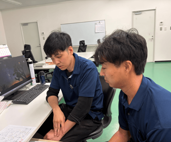 パソコンを見ながら打ち合わせをする社員
